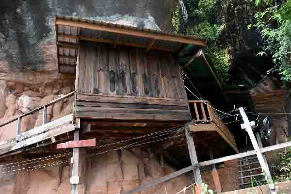 Cabane en bois accrochée à la falaise, lieu de méditation.