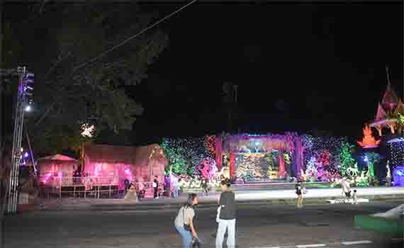 Festival d'Ok Phasa illuminé de nuit à Nong Khai avec des décorations colorées et des spectateurs dans la rue.