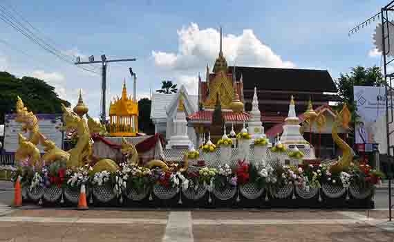 Char de procession décoré pour le festival Ok Phasa à Nong Khai, orné de structures de stupas blancs, de motifs de serpents naga dorés et de fleurs colorées.