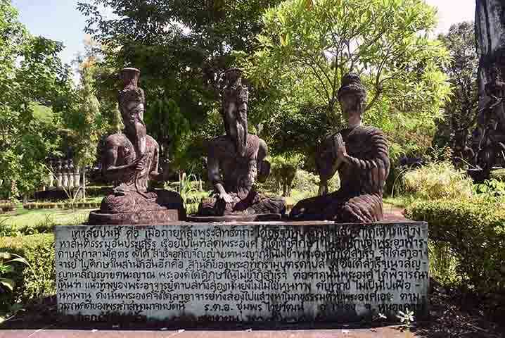 Trois statues d'ascètes ou de rishis assis en méditation derrière une stèle gravée en thaï, Sala Keoku