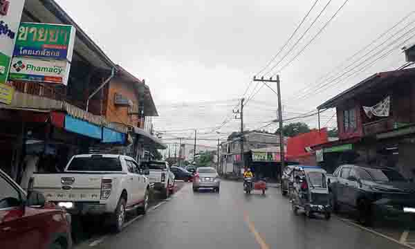 Scène de rue quotidienne à Bueng Kan, en Thaïlande, mêlant commerces et circulation locale.